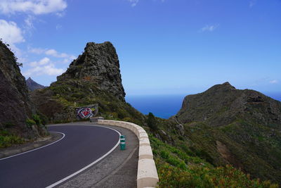 Road by mountain against blue sky