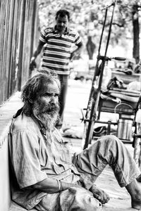 Male beggar sitting on footpath