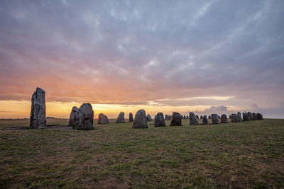 Panoramic shot of rocks on field against sky during sunset