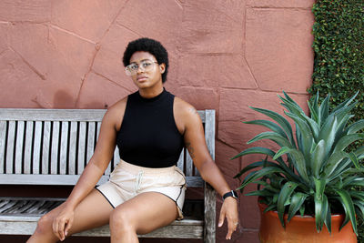 Portrait of smiling young woman sitting against wall