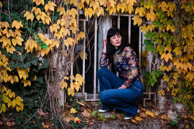 Full length of woman sitting on autumn leaves