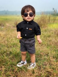 Full length portrait of cute boy standing on grass