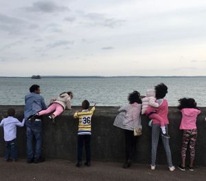 People standing by sea against sky