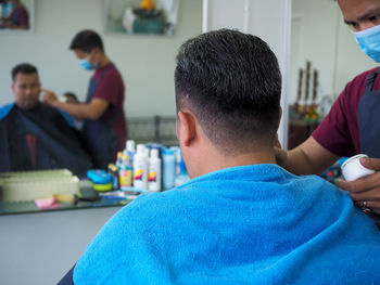 Man applying cream on male customer face