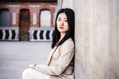 Portrait of confident chinese woman in city leaning on wall