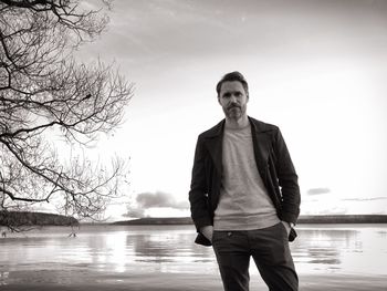 Portrait of man standing on lake against sky