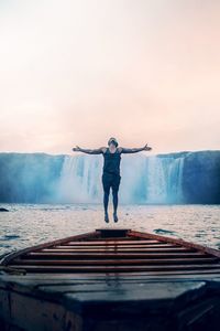 Full length rear view of man standing on shore against sky