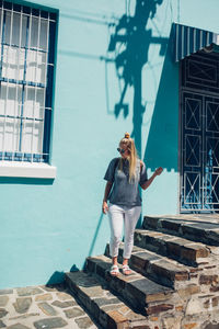 Full length of young woman standing against building