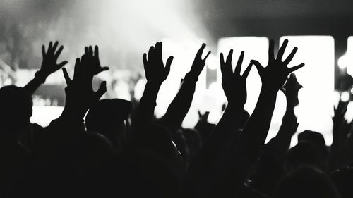 Silhouette people with arms raised during music concert