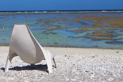 Deck chairs on shore at beach against sky