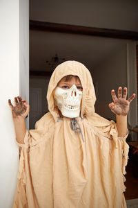 Portrait of young woman standing against wall