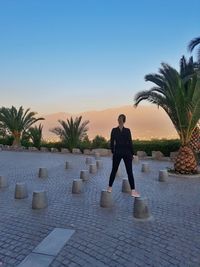 Rear view of woman standing by swimming pool against sky