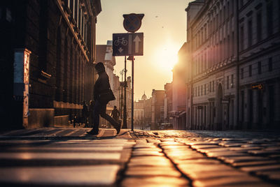 Side view of woman walking on street during sunrise