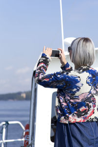 Rear view of woman standing on boat against sky