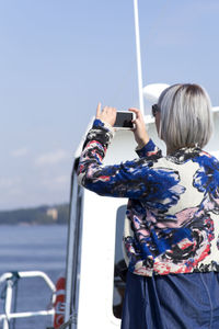 Rear view of person standing in sea against sky