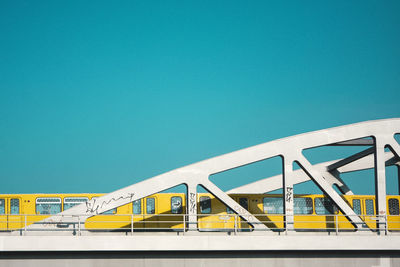 Low angle view of train on bridge against clear blue sky