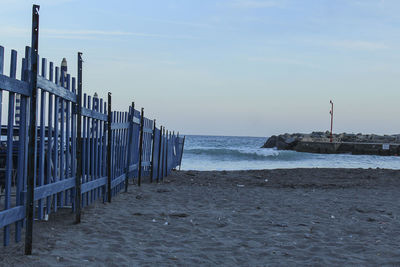 Wooden posts on beach against sky