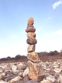 Stack of stones on field against sky