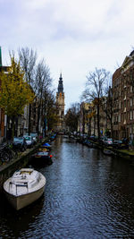 Boats in canal amidst buildings in city against sky