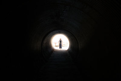 Rear view of silhouette man walking in tunnel