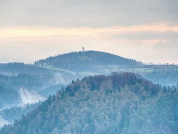 Treetops silhouette of the top of a hills in the fog, feel silence of misty valley in the morning