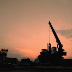 Silhouette crane at construction site against sky during sunset