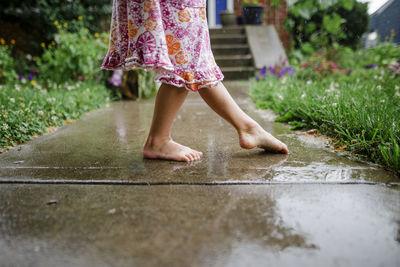 Low section of woman with arms raised in rain