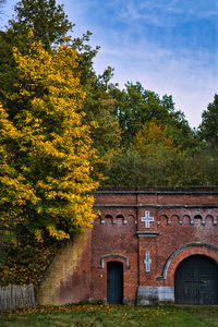 Trees and yellow house against sky during autumn