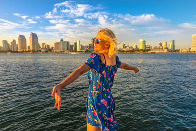 Smiling woman wearing sunglasses while standing in city