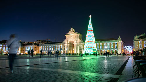 Group of people in illuminated building against sky at night
