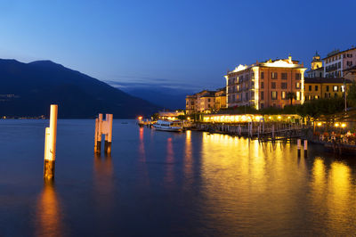 Ship on lake como by buildings against clear sky at dusk