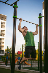 Muscular man exercising against sky at park