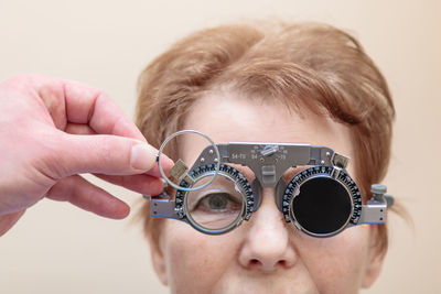 A male optometrist checks the eyesight of an adult woman with a trial frame