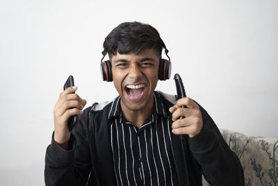 Portrait of smiling young man standing against white background