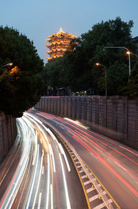 Light trails on road in city against sky