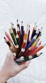 Close-up of hand holding multi colored pencils