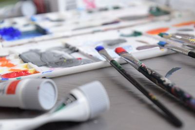 Close-up of colorful paints and paintbrushes on table