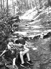 High angle view of smiling young woman sitting on rock in forest