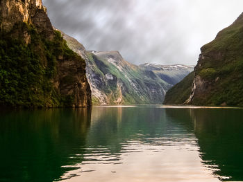 Scenic view of lake by mountains against sky