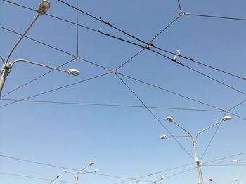 Low angle view of power cables against clear blue sky