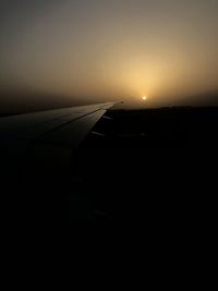 Airplane wing against sky during sunset
