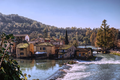 Buildings by lake against sky