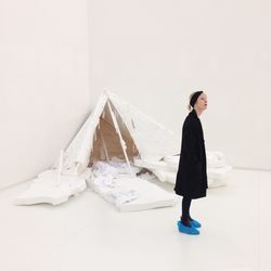 Side view of young woman standing against white wall