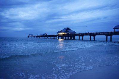 Pier on sea against cloudy sky