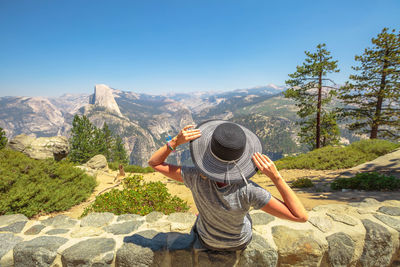 Rear view of woman looking at mountains against clear blue sky