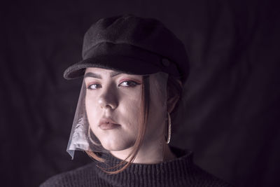 Portrait of man wearing hat against black background