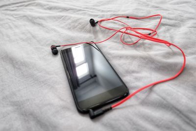 High angle view of smart phone on bed