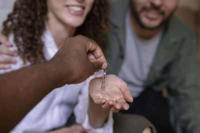 Hand of real estate agent giving keys to couple