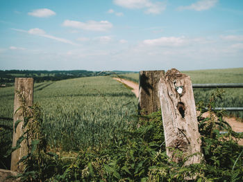 Wooden post on field against sky