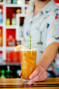 Midsection of bartender holding drink on table